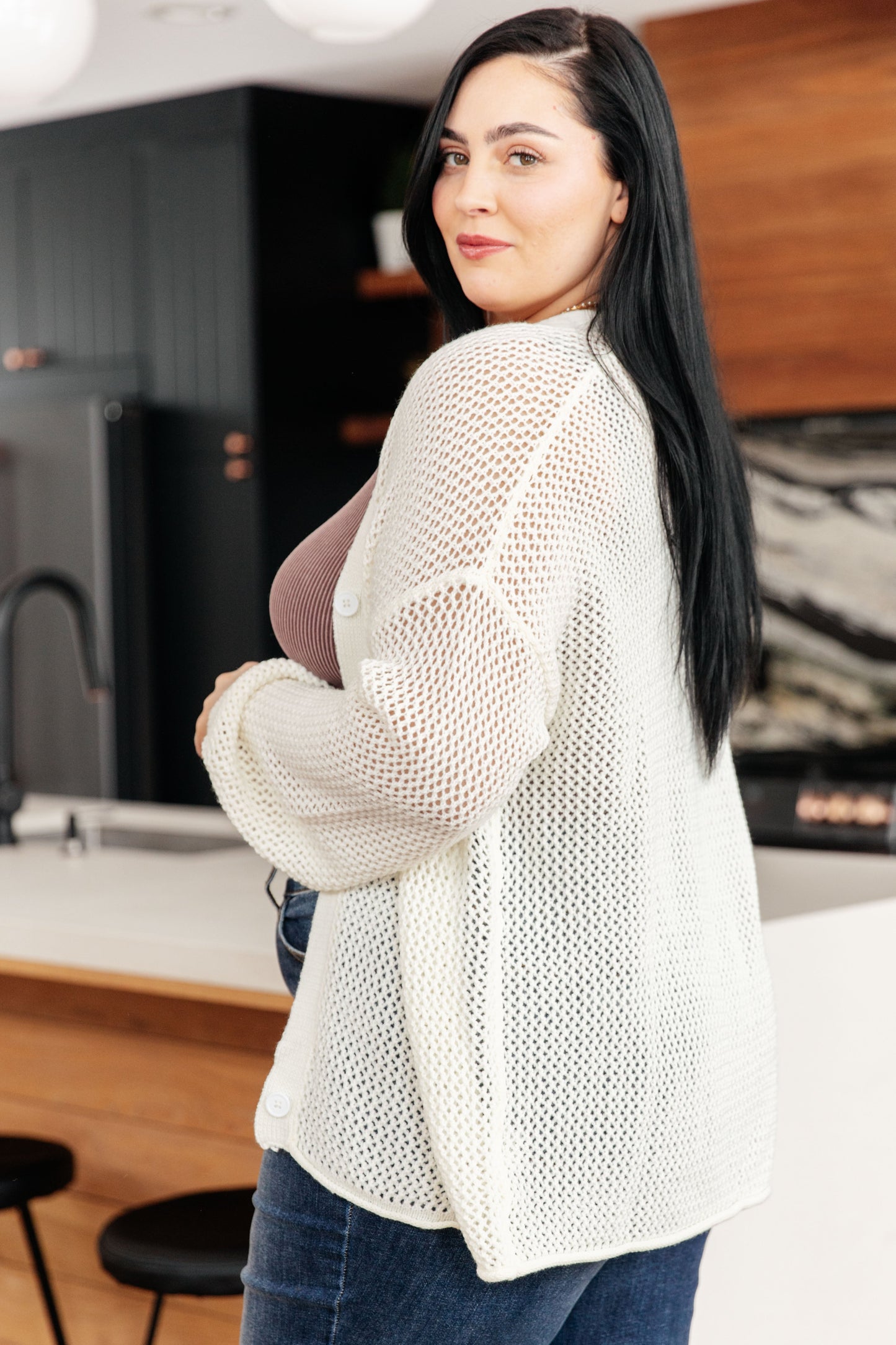 a woman wearing a white cardigan with jeans.