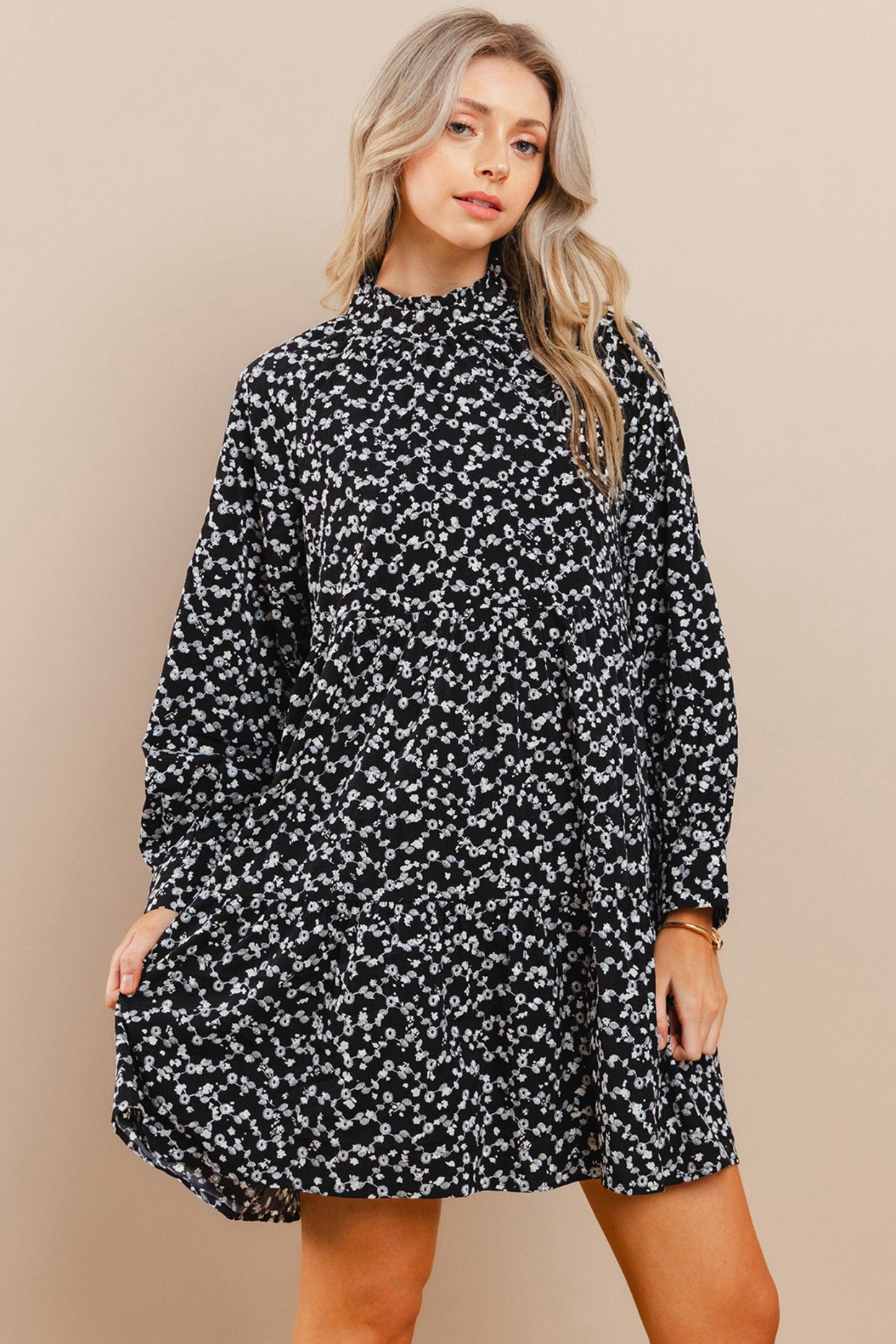 Woman wearing a black floral dress against a beige background