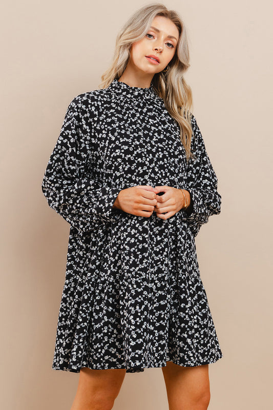 Woman wearing a black floral dress against a beige background.