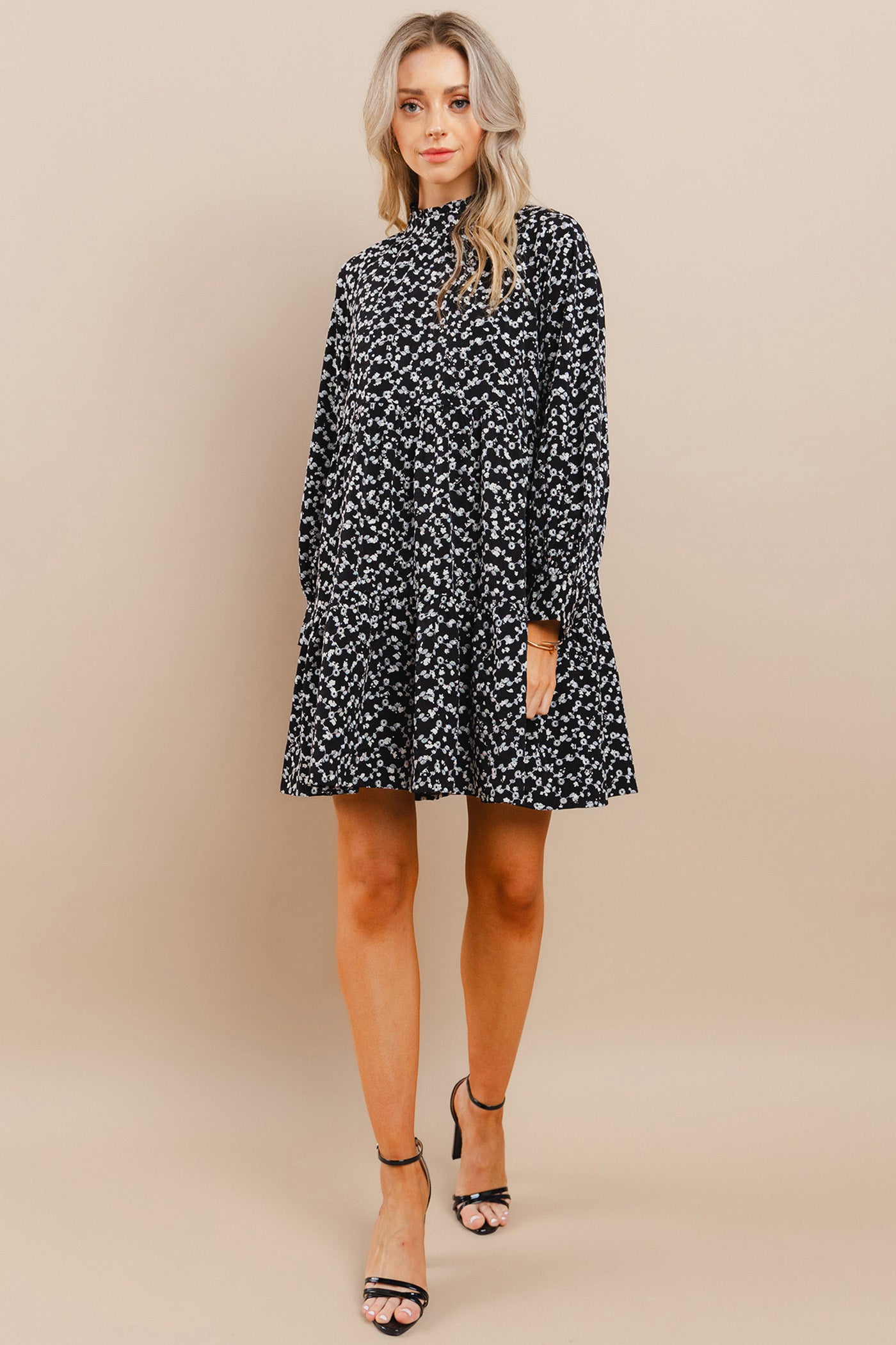 Woman wearing a black floral dress against a beige background