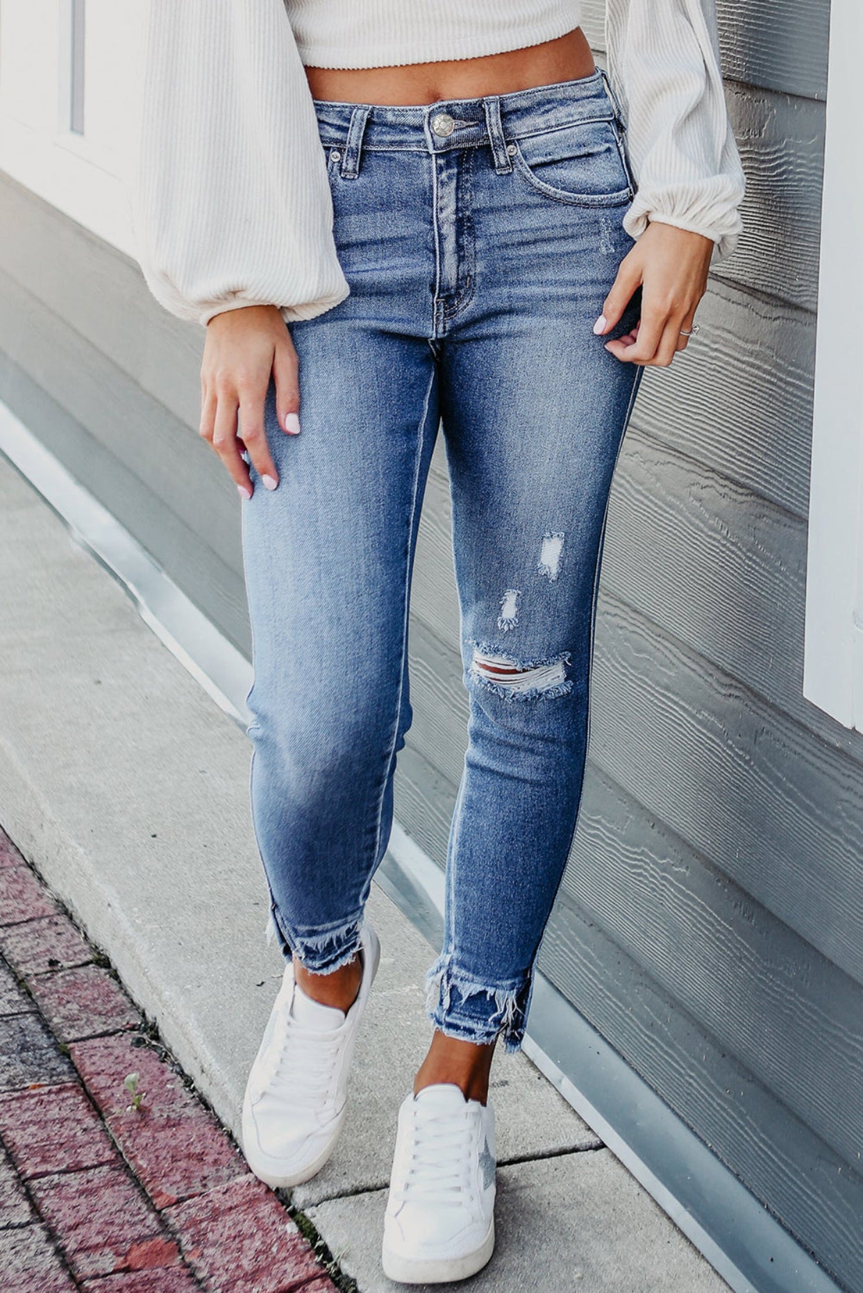 Women wearing blue jeans and white sneakers.