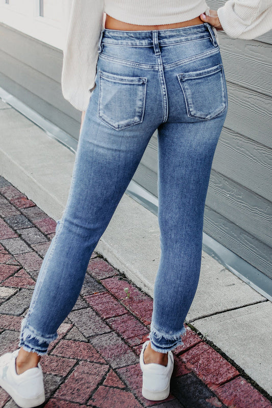 Women wearing blue jeans and white shoes on a sidewalk.