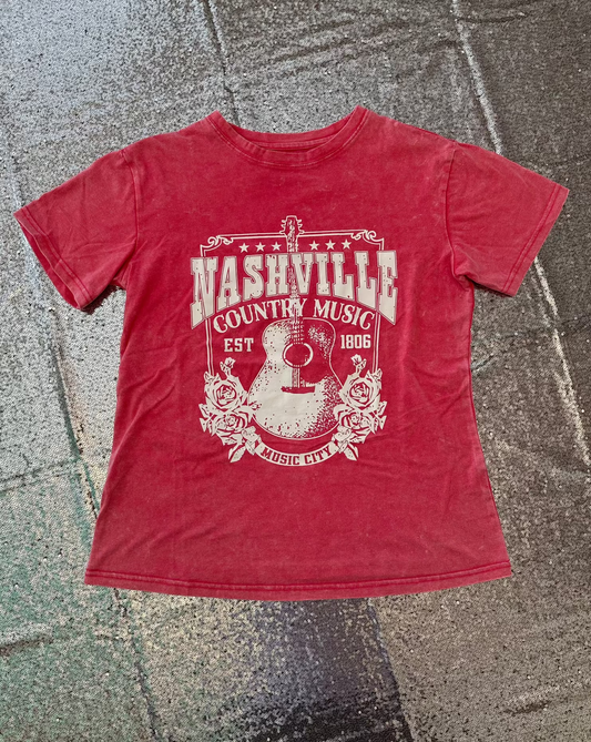 Pink t-shirt with 'Nashville Country Music' graphic on a textured surface