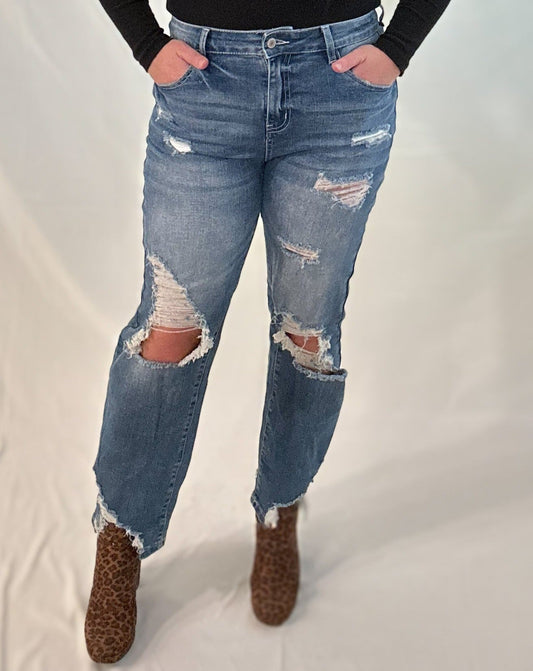 A woman wearing distressed blue jeans with a plain background