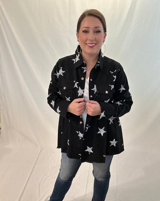 Woman wearing a black jacket with white star patterns on a plain background